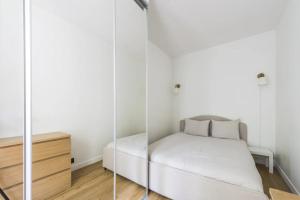 a small white bedroom with a bed and a dresser at Appartement 2 pièces 4 couchages tout confort in Neuilly-sur-Seine