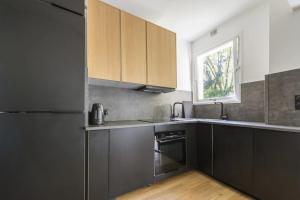 a kitchen with black cabinets and a window at Appartement 2 pièces 4 couchages tout confort in Neuilly-sur-Seine