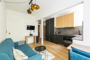 a living room with a blue couch and a kitchen at Appartement 2 pièces 4 couchages tout confort in Neuilly-sur-Seine