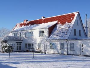 een wit gebouw met een rood dak in de sneeuw bij Ferienwohnung-Wiesenblick-mit-GRATIS-Leistungen in Thesenvitz