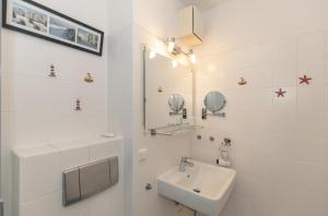 bagno bianco con lavandino e specchio di Haus-Olymp-Wohnung-5-371 a Kühlungsborn