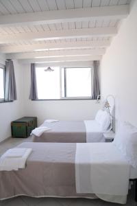 2 Betten in einem weißen Zimmer mit 2 Fenstern in der Unterkunft Casa Lussu in Lipari