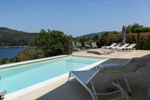 a swimming pool with chairs and a view of the water at Villa Gerês Emblematico - Piscina & Jacuzzi in Venda Nova