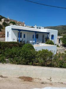 een wit huis met blauwe deuren op een strand bij The Kamari Blue Dome house in Kampos Paros