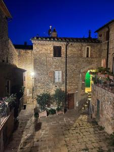 een oud stenen gebouw met 's nachts een straat bij 81Passi in Casale Marittimo