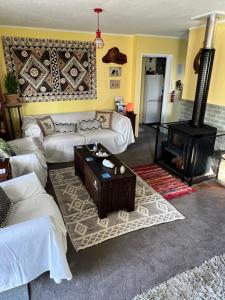 uma sala de estar com sofás brancos e um fogão a lenha em Karikari Lodge em Tokerau Beach