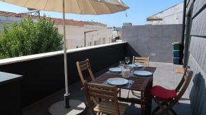una mesa de madera con sillas y una sombrilla en el balcón en SottoMayor Best Residence, en Figueira da Foz