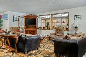 sala de estar con muebles de cuero y TV en Quality Inn, en Saint Ignace