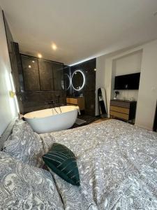 - une chambre avec un grand lit et une baignoire dans l'établissement Gîte Liberta - Equipé d'une balneo entre Dinan et St Malo, à Saint-Pierre-de-Plesguen