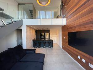 a living room with a black couch and a kitchen at Cobertura aconchegante perto do shopping independência, home office, garagem in Juiz de Fora