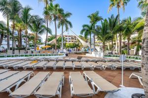 a row of lounge chairs and palm trees at a resort at Dúplex en las Americas 3014 in Arona