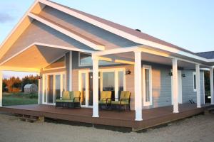 ein Haus mit einer Veranda und Stühlen auf einer Terrasse in der Unterkunft Luxueux chalet sur la plage - Baie des Chaleurs in Caraquet