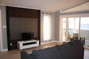 a living room with a couch and a flat screen tv at Luxueux chalet sur la plage - Baie des Chaleurs in Caraquet