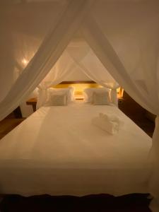 a white bed with white sheets and pillows at Pantai Atins in Atins