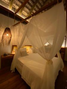 a bedroom with a white bed with a mosquito net at Pantai Atins in Atins