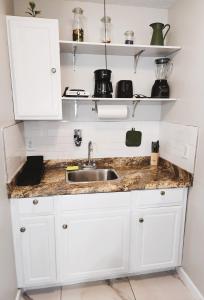 una cocina con armarios blancos y fregadero en Adorable Mini Suite in Tampa, en Tampa