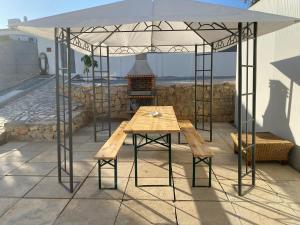 - une table et un banc sous une tente sur une terrasse dans l'établissement Moradia Olival- BBQ, 2 Quartos, Quintal, à Albufeira