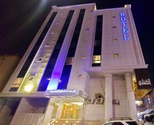 un edificio de hotel con un cartel de luz azul en رام جده للشقق الفندقيه Ram Jeddah, en Yeda