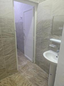y baño con lavabo blanco y ducha. en شقق وادي ذنه, en Salalah