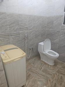 a bathroom with a toilet and a trash can at شقق وادي ذنه in Salalah