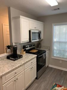 a kitchen with white cabinets and a black stove top oven at Comfy, Stylish Townhome Near I-20! in Augusta