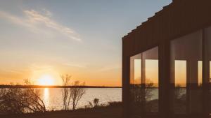 a sunset over a body of water with a building at Mysa Nordic Spa & Resort in Saint Peters