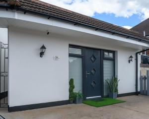 a white house with a black door at Luxury one bedroom guesthouse M6, Junction 10 Walsall in Willenhall