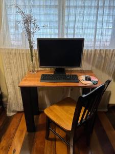 a desk with a computer monitor and a chair at The Coral Casa in Caye Caulker