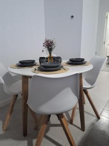 a dining room table with two white chairs and a table with plates at Loft Turístico Bouzas in Vigo