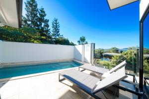 a patio with a swimming pool and two white chairs at 3 Bedroom Holiday Home Valley Views in Airlie Beach in Airlie Beach