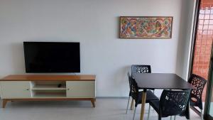 マセイオにあるConforto e tranquilidade, 2 quartos na Pajuçaraのテレビとテーブルと椅子のあるリビングルーム