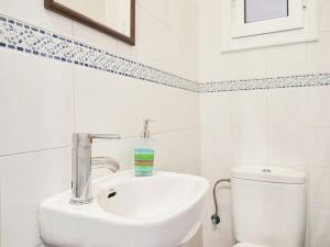 a white bathroom with a sink and a toilet at Belvilla by OYO Rambla Paris Apartment in Barcelona +26 photos