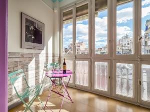 a purple table and chairs in a room with windows at Belvilla by OYO Rambla Paris Apartment in Barcelona
