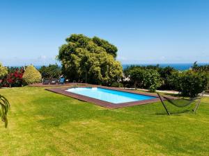 a swimming pool in a field of grass with the ocean in the background at beautiful 5 bedroom property with sea view, private tennis court private pool in Arucas