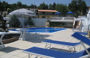 a pool with chairs and tables and an umbrella at Agriturismo I Tre Ulivi in Paternopoli