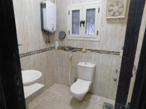 La salle de bains est pourvue de toilettes blanches et d'un lavabo. dans l'établissement فيلا للايجار مفروش بمدينة العبور, à ‘Ezbet el-Insha