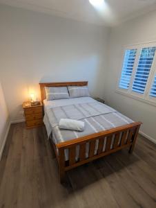a bedroom with a large bed with a wooden bed frame at Immaculate 2-Beds Entire House Chermside Brisbane in Brisbane