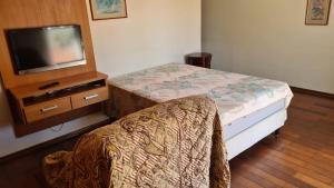 1 dormitorio con 1 cama, TV y silla en Casa centro Serra Negra en Serra Negra