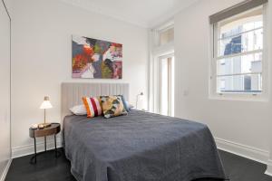 a white bedroom with a bed and a window at Orange Stay Apartments Potts Point in Sydney