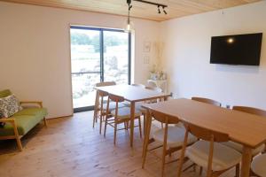 a living room with a table and chairs and a tv at 1日1組様限定 黒姫山の絶景を楽しむ貸切サウナ付き一軒家 in Shinano