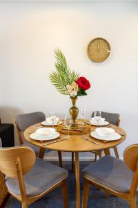 une table avec des verres et un vase avec une rose dessus dans l'établissement Harmony Hideout 2 bed 2 bath, à Christchurch