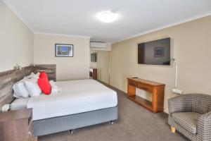 a bedroom with a bed and a chair and a television at Boulevard Motor Inn in Mildura