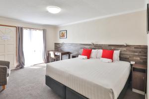 a bedroom with a large bed with red pillows at Boulevard Motor Inn in Mildura