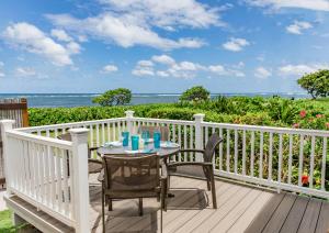 a table and chairs on a deck with a view of the ocean at OceanFront Kauai - Harmony TVNC 4247 in Kapaa