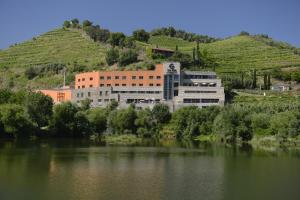 um edifício sobre uma colina ao lado de um corpo de água em Vila Gale Collection Douro em Lamego