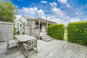 Casa con terraza de madera con mesa y bancos en Greenhaven with wi-fi, en Taupo