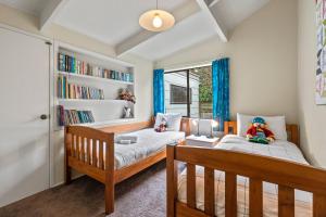 1 dormitorio con 2 camas y estante para libros en Greenhaven with wi-fi, en Taupo