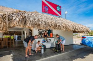 un grupo de personas de pie en frente de un bar en Bloozz resort Bonaire, en Kralendijk