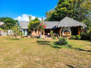 ein Haus mit einem Grasdach und einem Hof in der Unterkunft Charlie's Villa in Gili Air