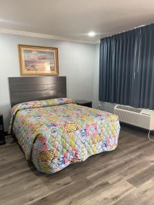 a bedroom with a large bed with a colorful bedspread at Travel Inn Gilroy in Gilroy